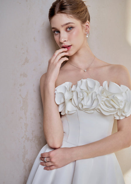 Graduate in a white LARMES Peony A-line dress with floral ruffles at the bust